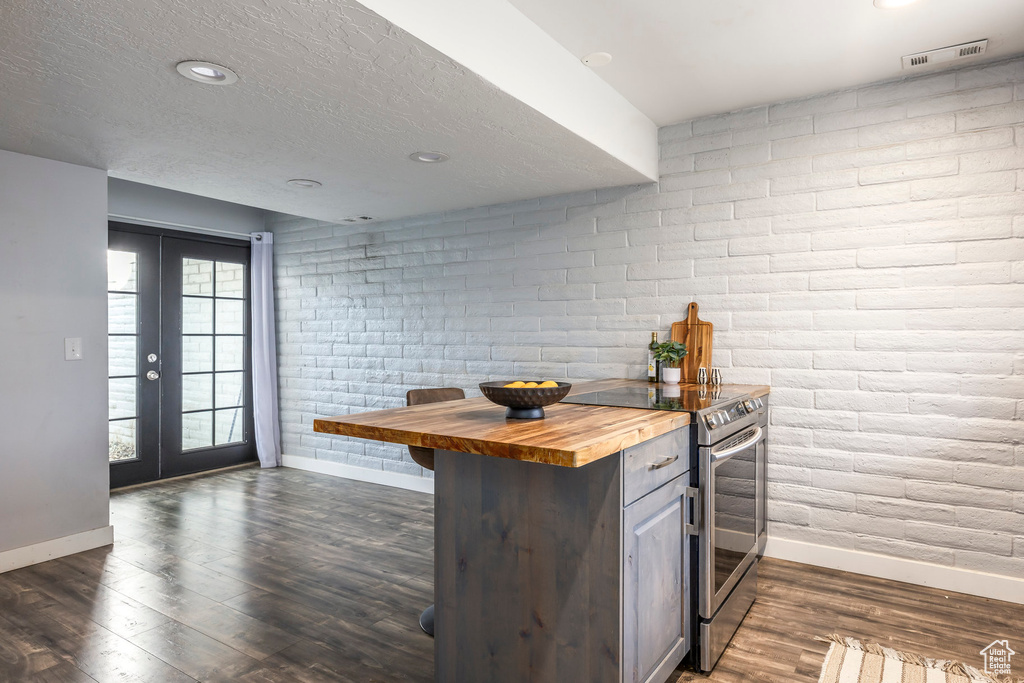 Kitchen with butcher block countertops, stainless steel electric range oven, dark wood-style flooring, french doors, and a textured ceiling