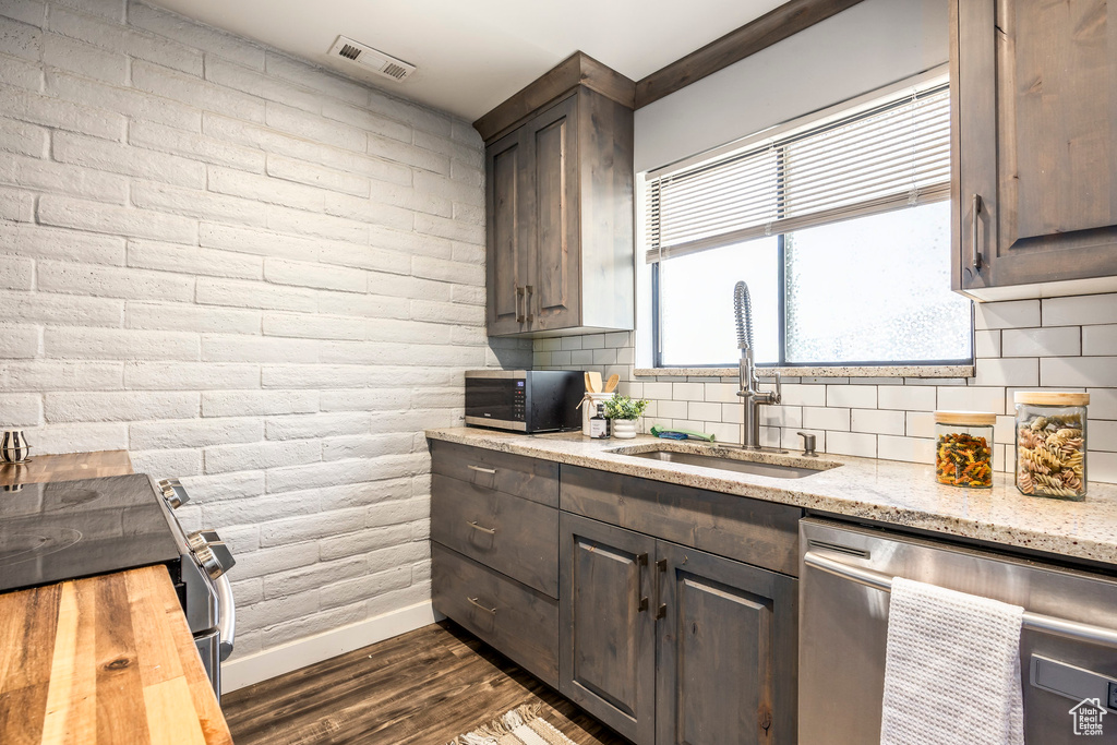 Kitchen with stainless steel appliances, dark wood-style flooring, tasteful backsplash, butcher block countertops, and dark brown cabinets
