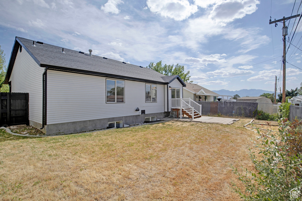Back of property with a fenced backyard and a shingled roof