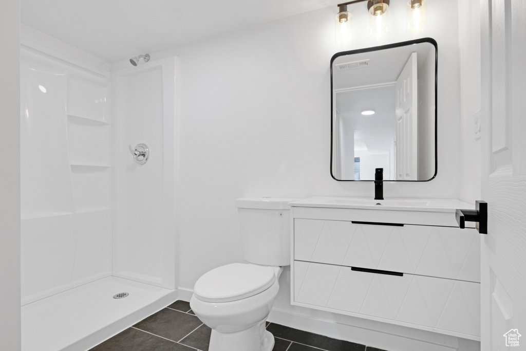 Bathroom with tile patterned floors, vanity, and a shower
