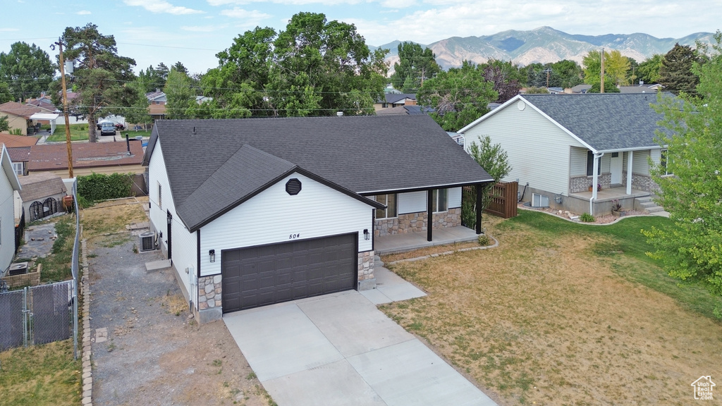 Ranch-style home featuring covered porch, stone siding, concrete driveway, and a garage
