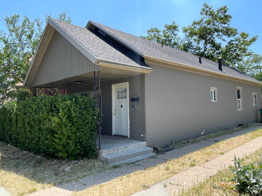 Ranch-style home featuring roof with shingles and stucco siding