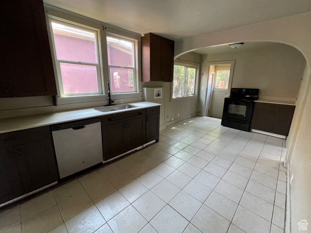 Kitchen featuring black range with electric stovetop, stainless steel dishwasher, arched walkways, and light countertops