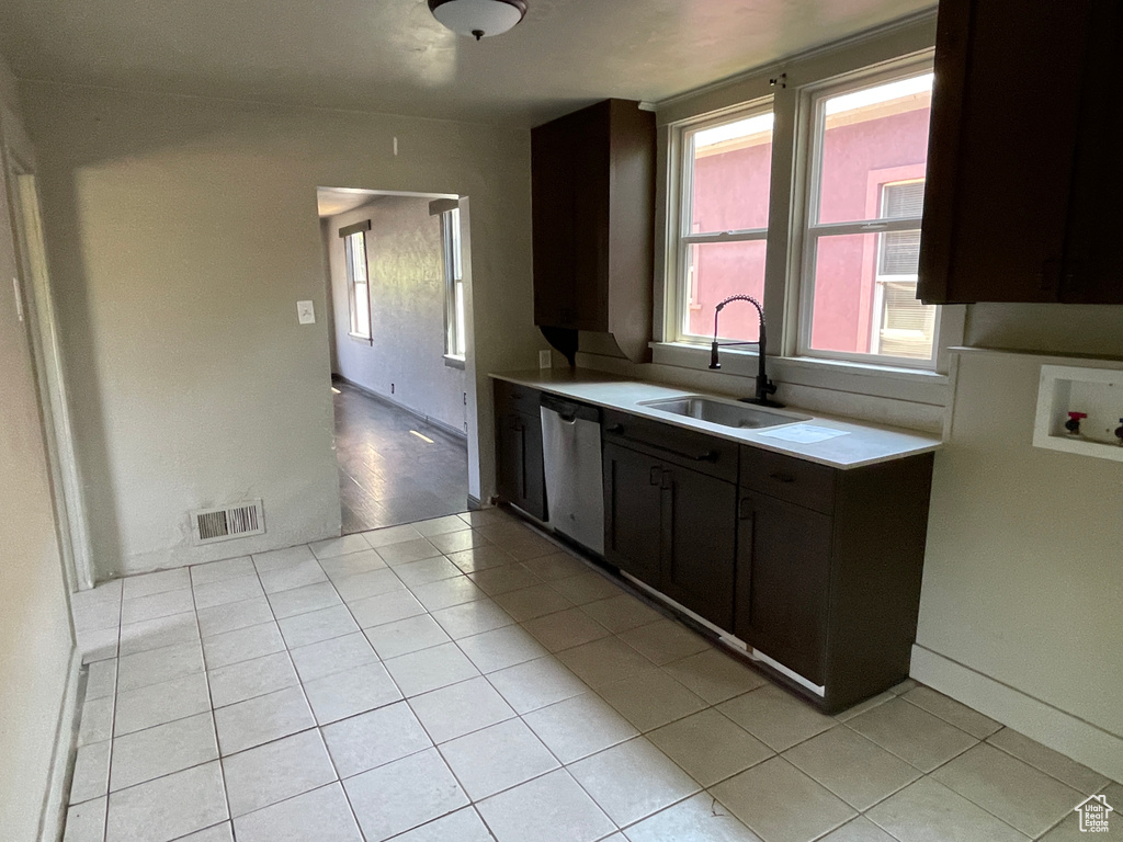 Kitchen with stainless steel dishwasher, light countertops, and light tile patterned floors