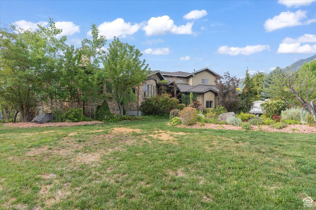View of property hidden behind natural elements featuring a front yard