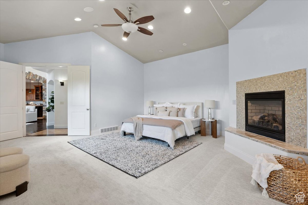 Carpeted bedroom featuring vaulted ceiling, a fireplace with raised hearth, a ceiling fan, recessed lighting, and arched walkways