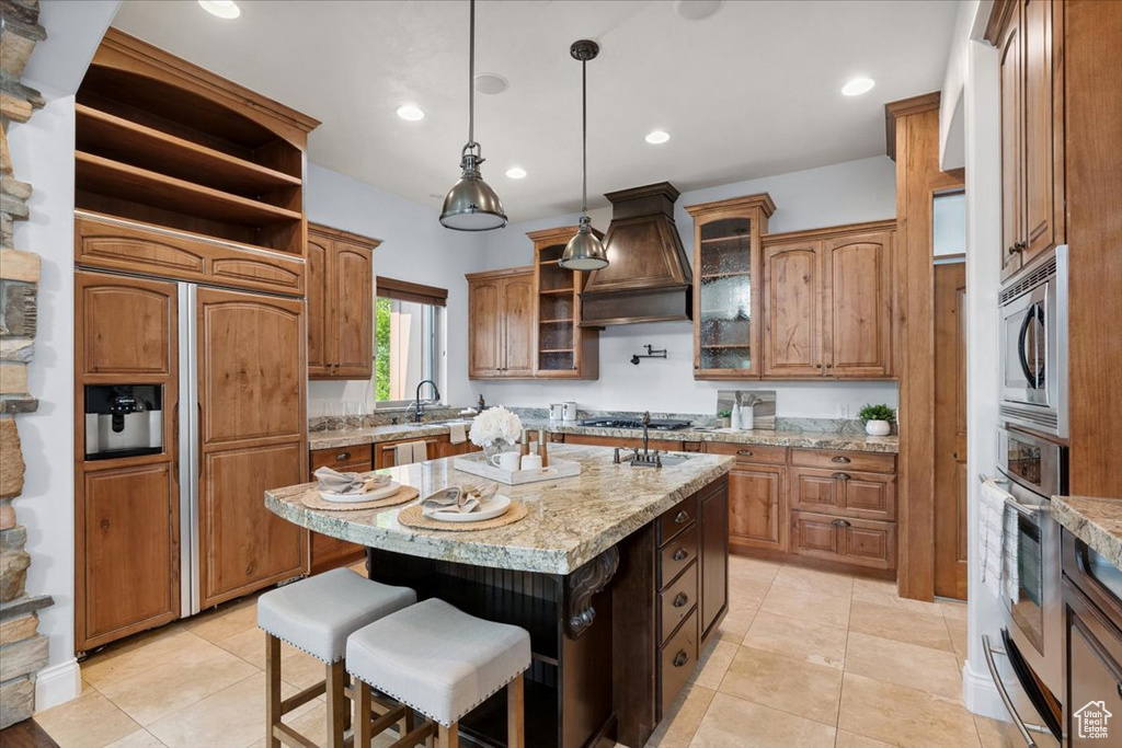 Kitchen with custom range hood, built in appliances, a warming drawer, a kitchen island, and open shelves