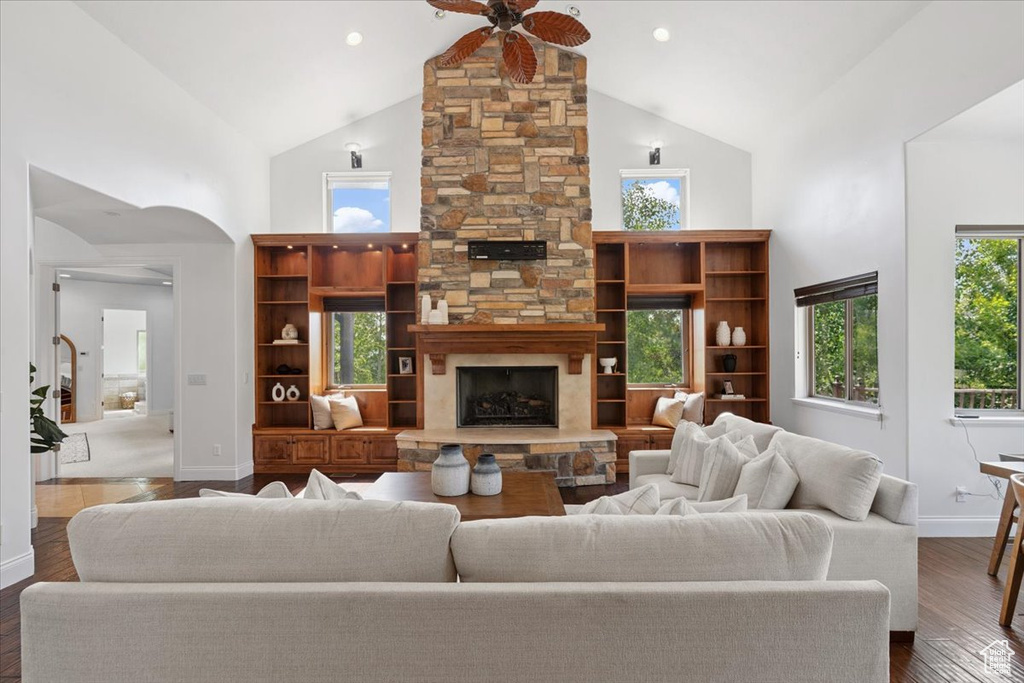 Living area with high vaulted ceiling, ceiling fan, wood finished floors, and a stone fireplace