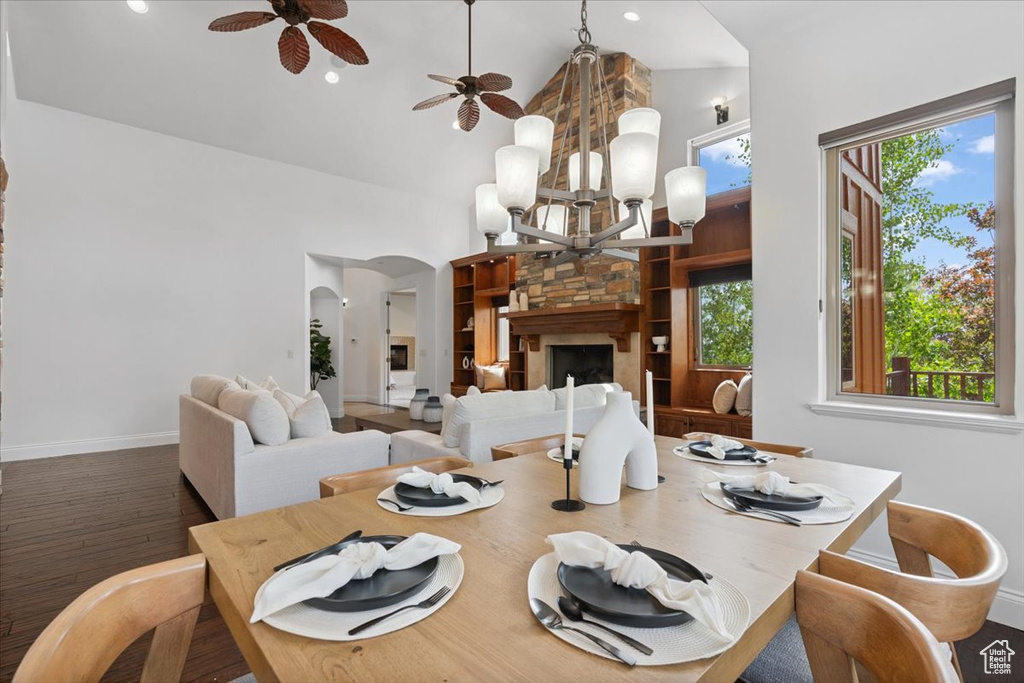Dining room featuring high vaulted ceiling, a chandelier, arched walkways, ceiling fan, and wood finished floors