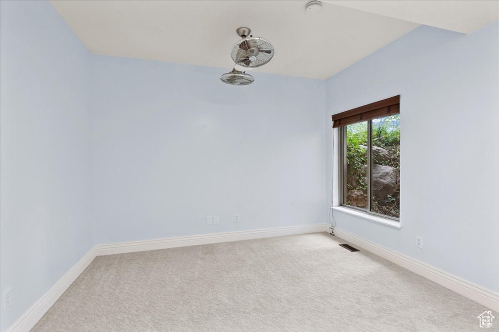 Carpeted spare room featuring baseboards and a smoke detector