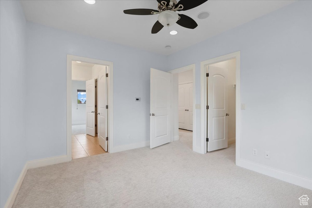 Unfurnished bedroom featuring carpet floors, ensuite bathroom, and a ceiling fan