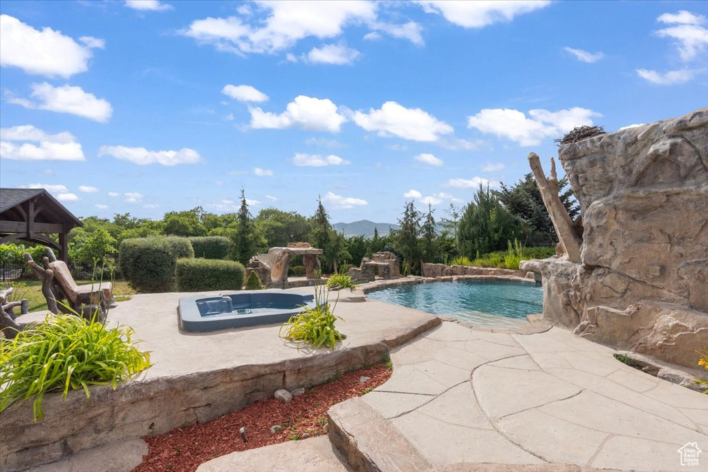 Swimming pool with a gazebo, a patio, and an in-ground hot tub