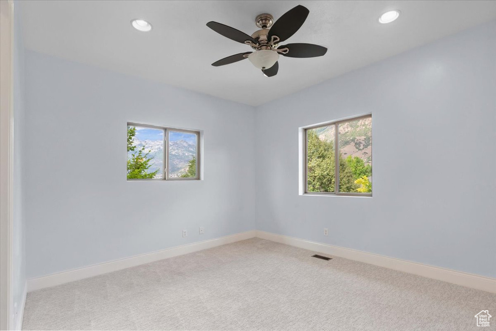 Carpeted spare room with plenty of natural light, a ceiling fan, and recessed lighting