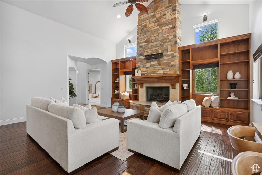 Living room featuring high vaulted ceiling, ceiling fan, arched walkways, dark wood finished floors, and a fireplace