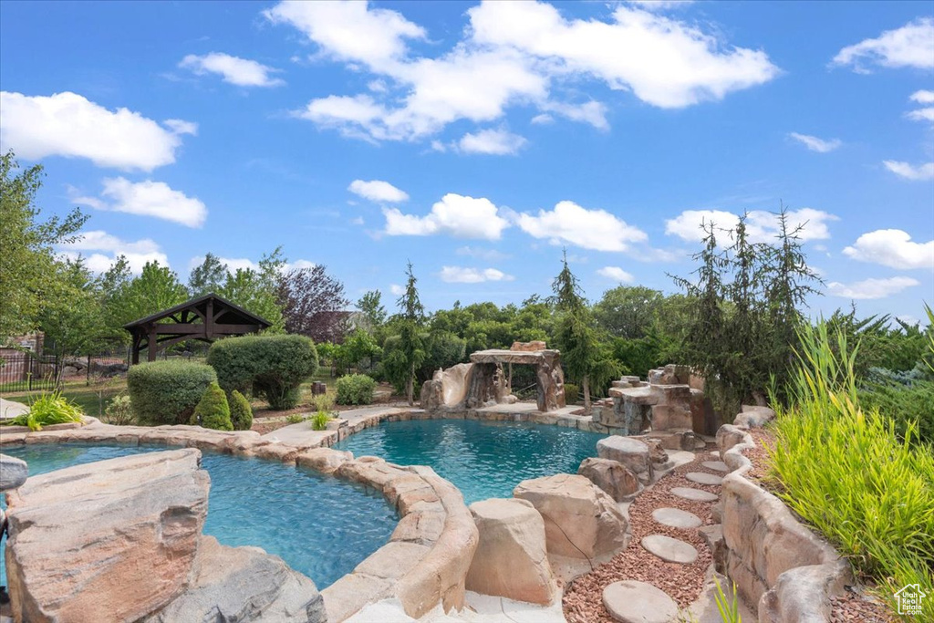 View of pool with a gazebo and a pool with connected hot tub