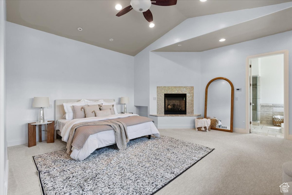Carpeted bedroom featuring lofted ceiling, a fireplace with raised hearth, connected bathroom, a ceiling fan, and recessed lighting