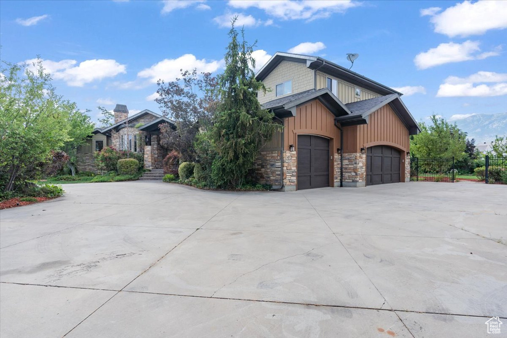 View of front facade featuring stone siding, concrete driveway, board and batten siding, and a garage
