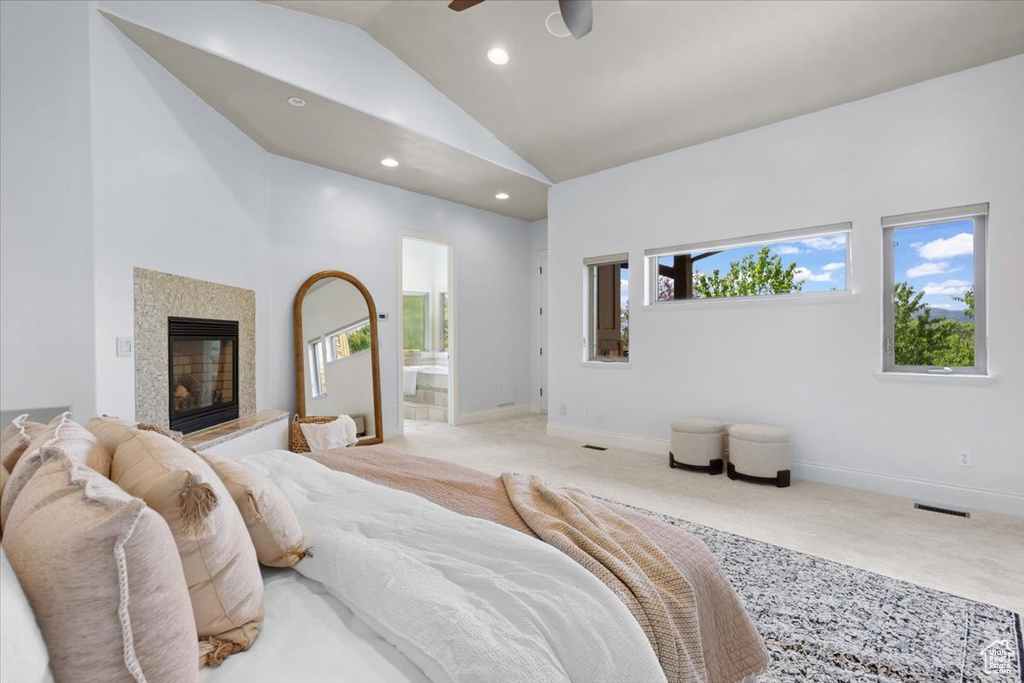 Bedroom with light carpet, lofted ceiling, recessed lighting, a glass covered fireplace, and connected bathroom