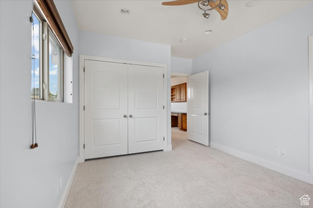 Unfurnished bedroom with light carpet, a closet, and ceiling fan