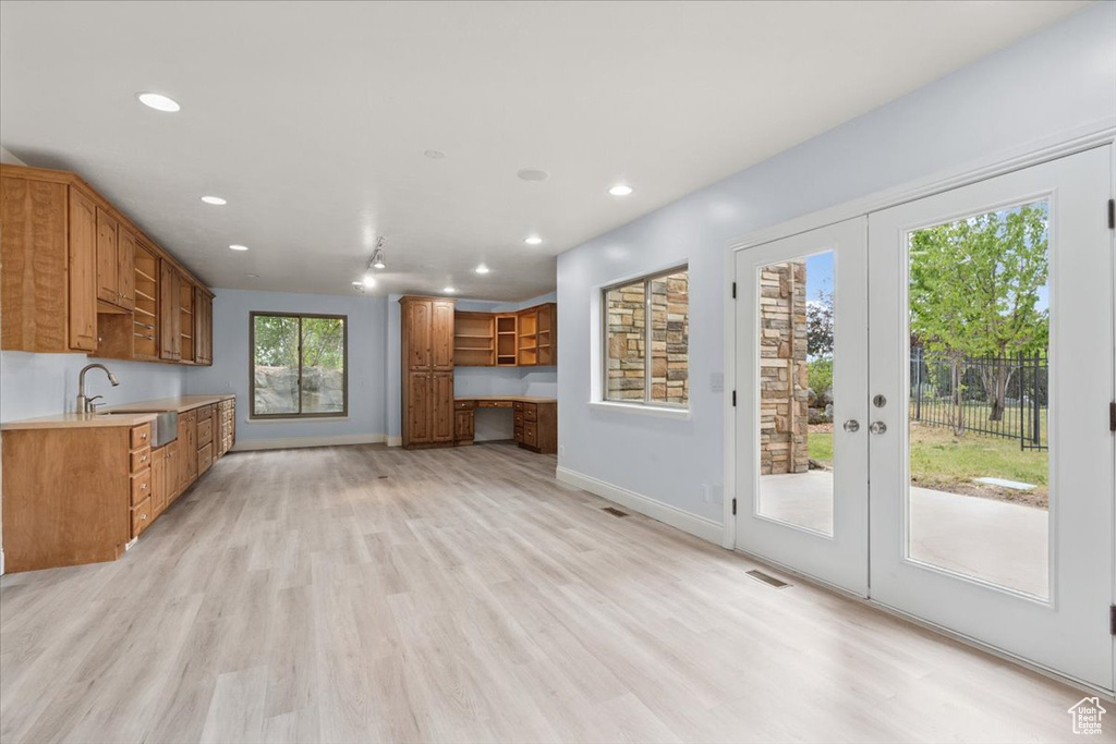 Kitchen with recessed lighting, brown cabinetry, light countertops, open shelves, and light wood finished floors