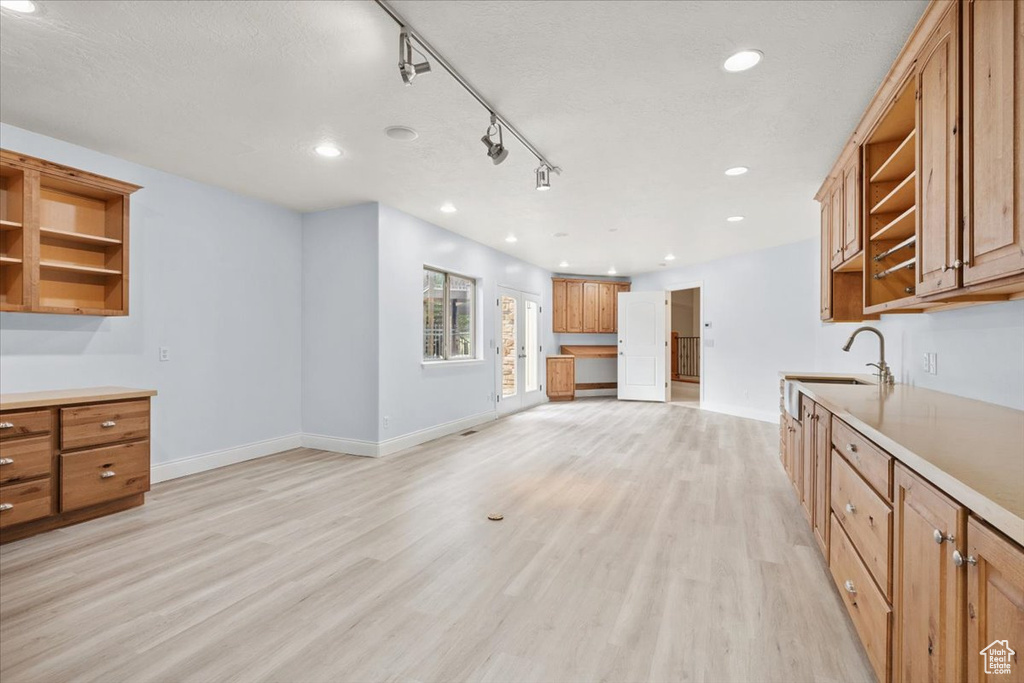 Kitchen featuring open shelves, light wood-type flooring, brown cabinetry, recessed lighting, and light countertops