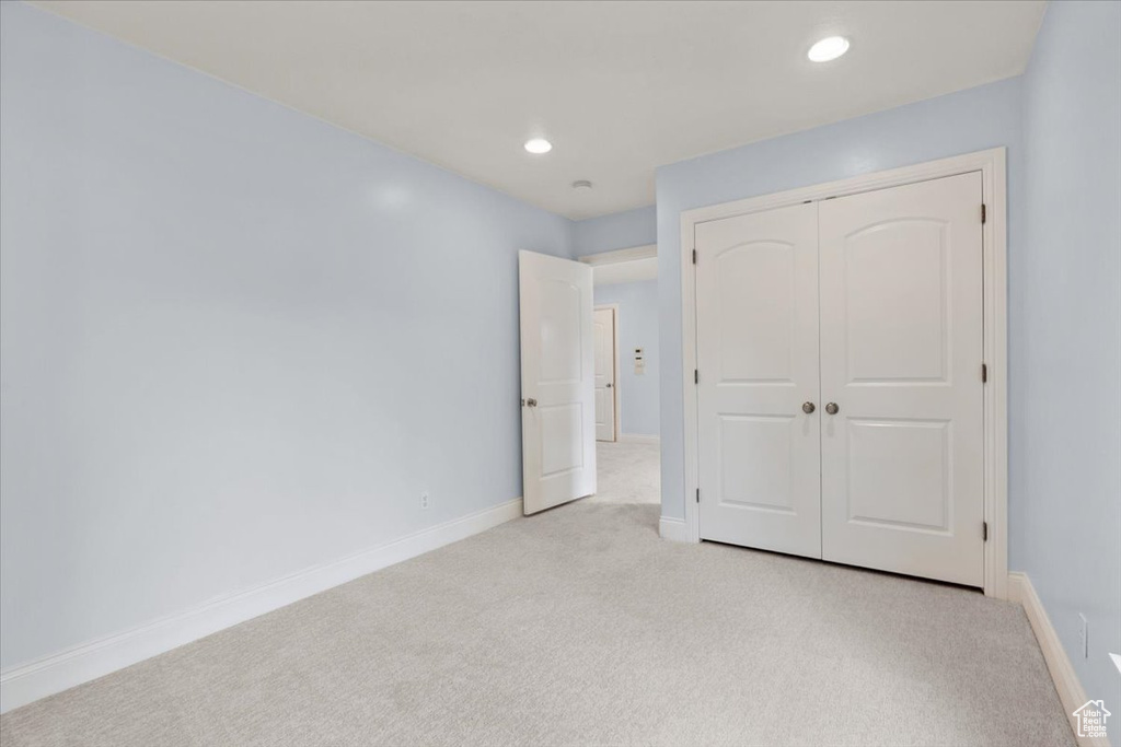 Unfurnished bedroom with light colored carpet, a closet, and recessed lighting