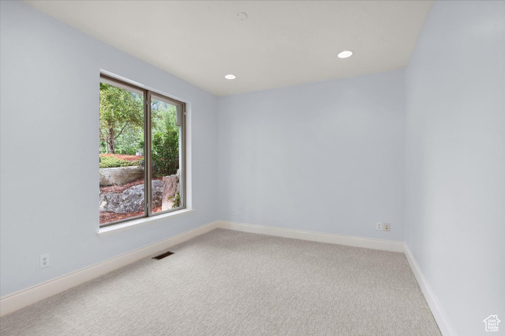 Empty room with light carpet and recessed lighting