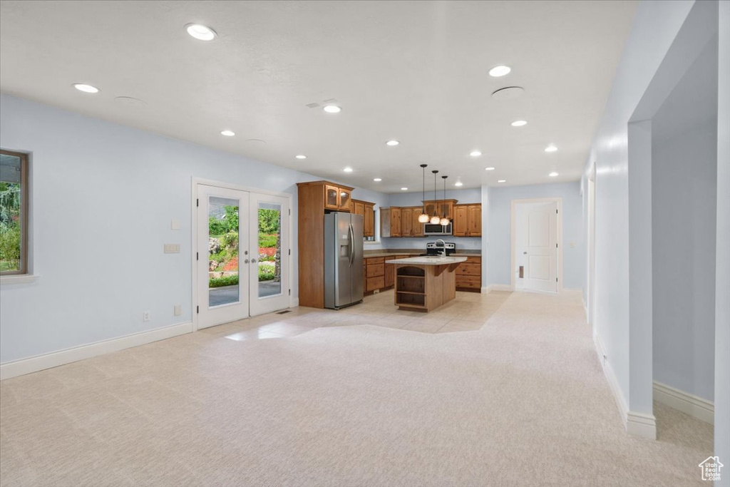 Kitchen with appliances with stainless steel finishes, open floor plan, light colored carpet, recessed lighting, and brown cabinets