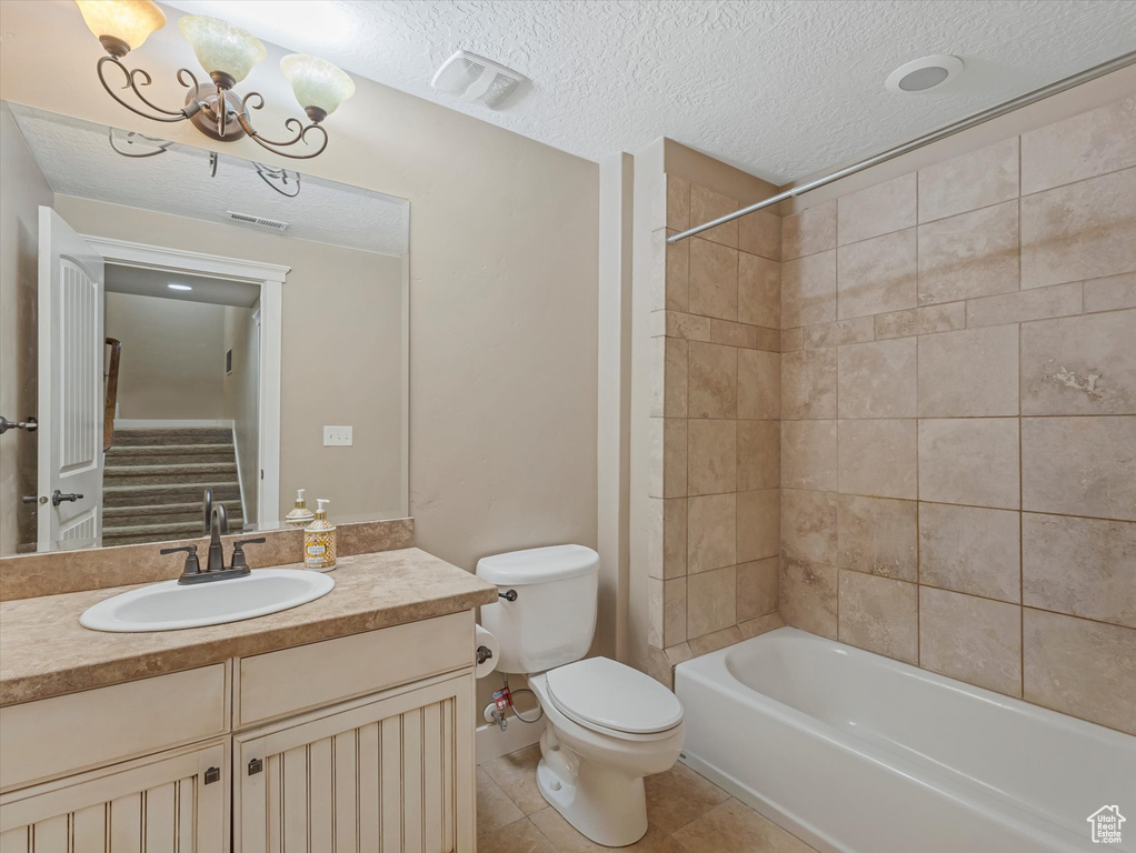 Bathroom with vanity, washtub / shower combination, a textured ceiling, a chandelier, and tile patterned flooring