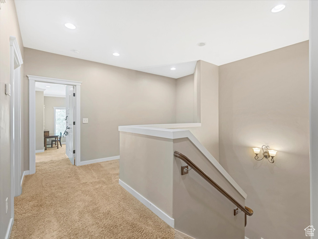 Corridor with an upstairs landing, light carpet, and recessed lighting