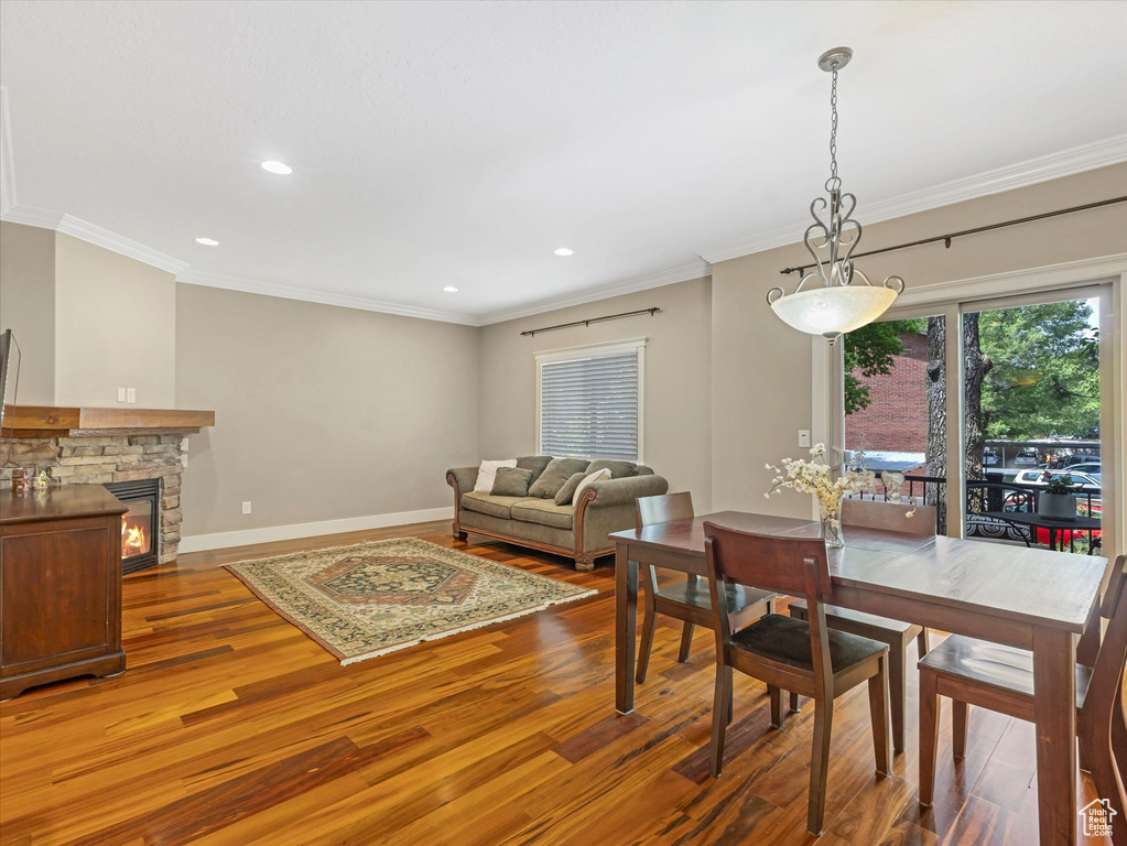 Dining space with wood finished floors, recessed lighting, ornamental molding, and a fireplace