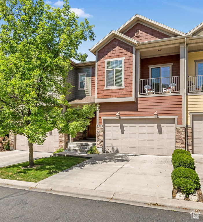 View of front of house featuring an attached garage, stone siding, and concrete driveway