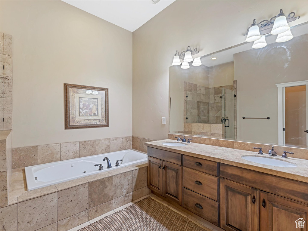 Bathroom featuring double vanity, a whirlpool tub, a stall shower, and tile patterned flooring