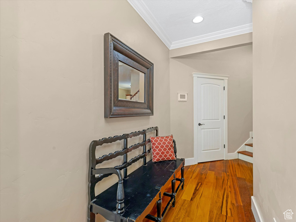 Corridor with ornamental molding, wood finished floors, and recessed lighting