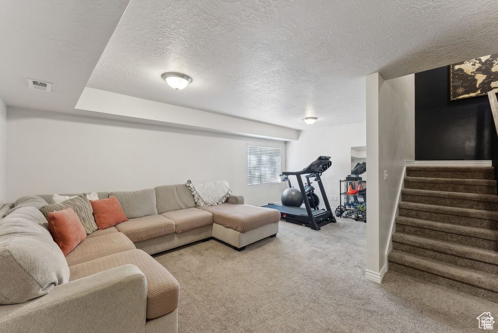 Carpeted living area featuring a textured ceiling and stairway