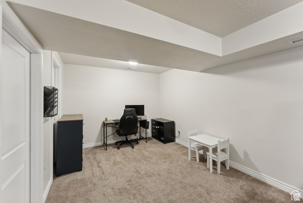 Carpeted home office featuring baseboards and a textured ceiling