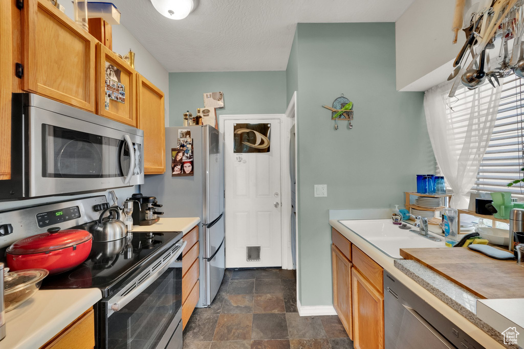 Kitchen with appliances with stainless steel finishes, light countertops, and stone finish flooring