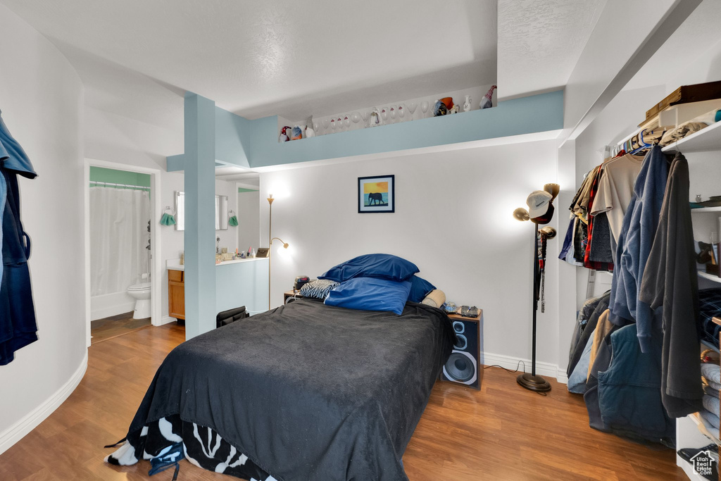 Bedroom with wood finished floors and connected bathroom