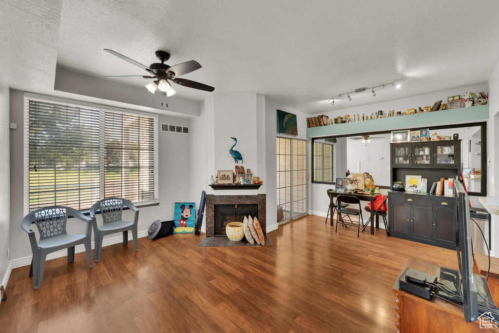 Living room with ceiling fan, a textured ceiling, wood finished floors, and a high end fireplace