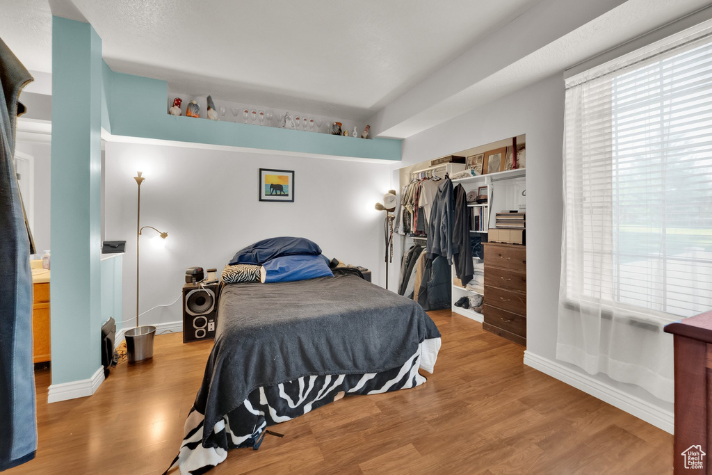 Bedroom with wood finished floors, multiple windows, and a closet