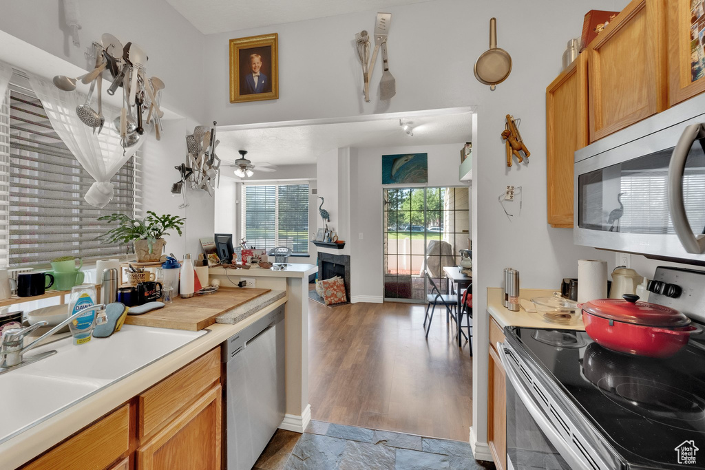 Kitchen with stainless steel appliances, light countertops, ceiling fan, and wood finished floors