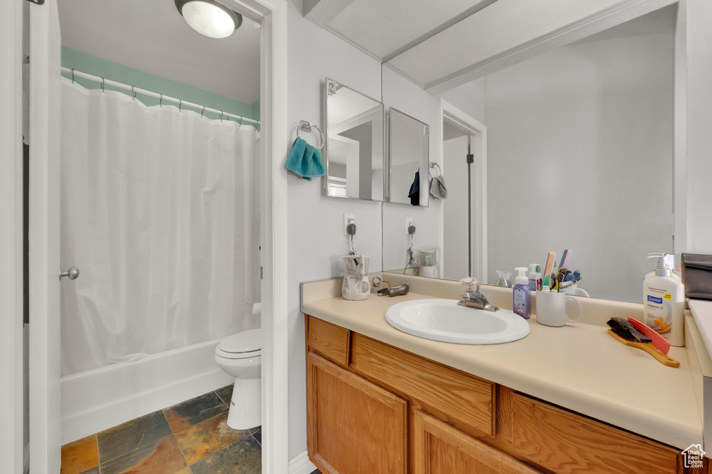 Full bathroom with stone finish flooring, vanity, and shower / bath combination with curtain