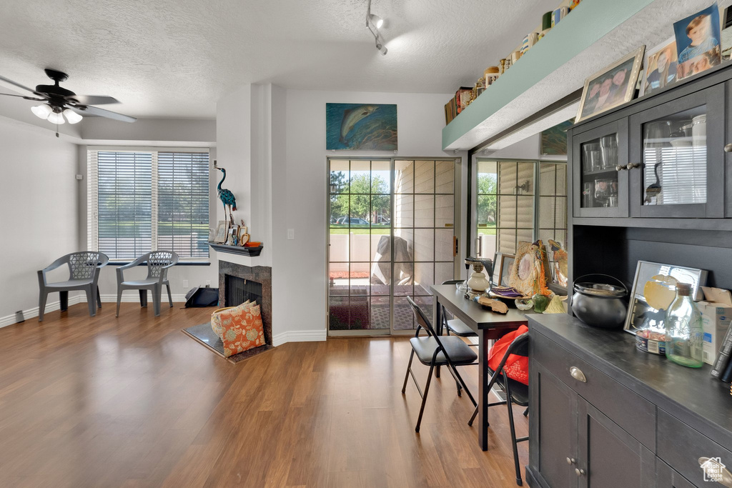 Home office featuring a textured ceiling, wood finished floors, a ceiling fan, and a tiled fireplace