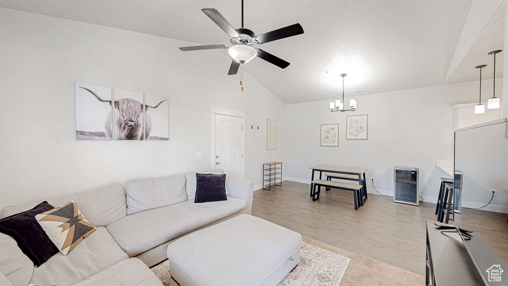 Living area with ceiling fan, beverage cooler, light wood-style flooring, a chandelier, and high vaulted ceiling