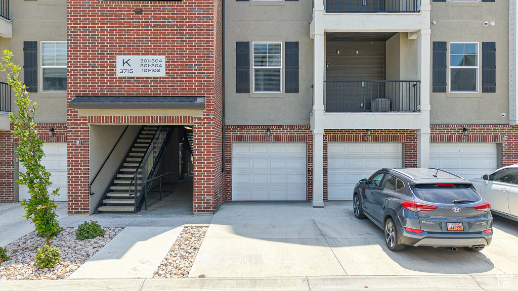 View of property with a garage, driveway, and stairs