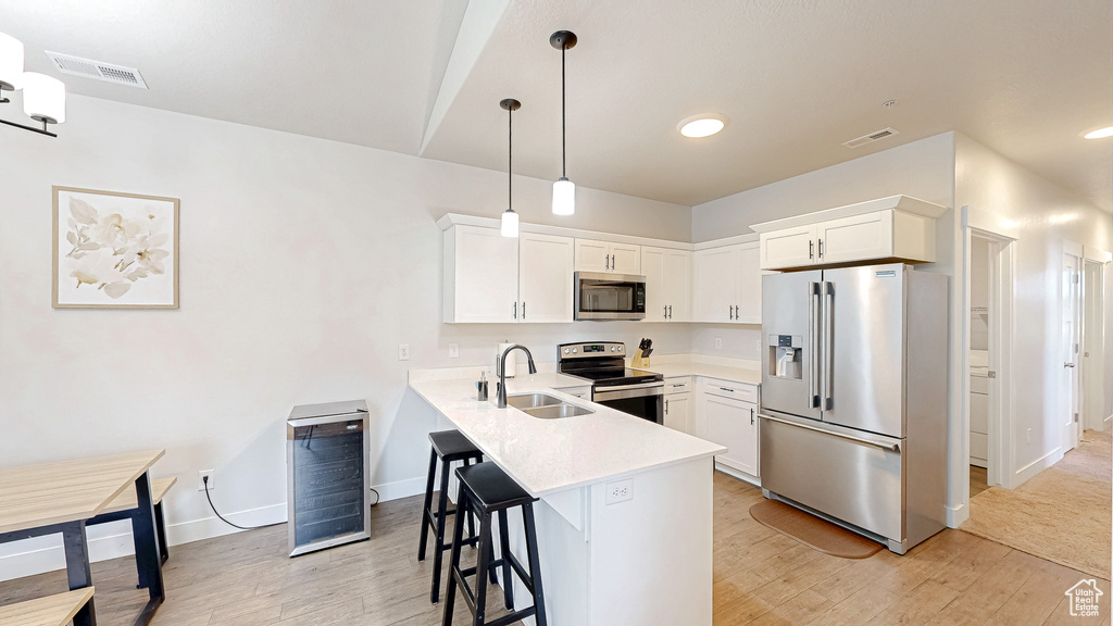 Kitchen featuring stainless steel appliances, light countertops, light wood-type flooring, a peninsula, and recessed lighting