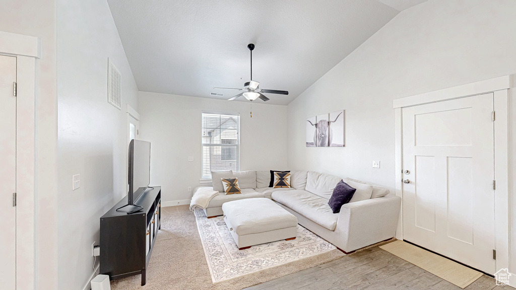 Living room featuring vaulted ceiling, ceiling fan, and light wood-type flooring