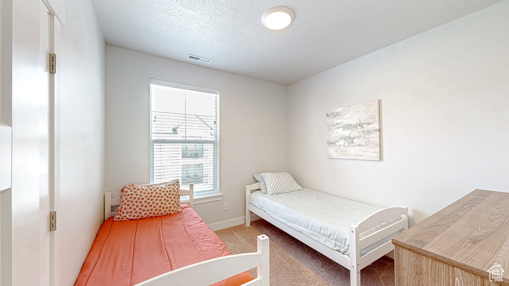 Bedroom with light carpet and a textured ceiling