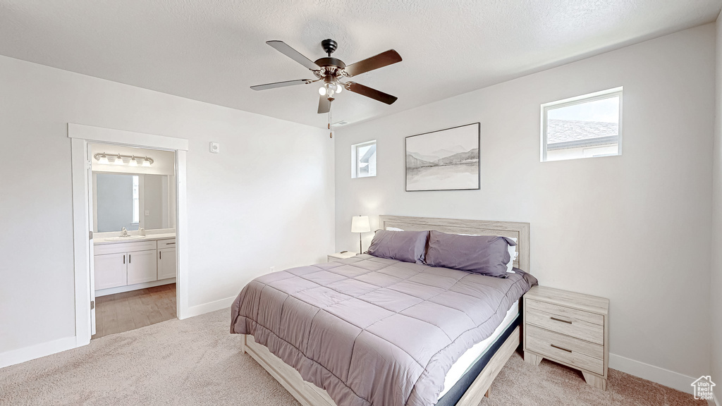 Bedroom featuring light colored carpet, ensuite bath, and a ceiling fan