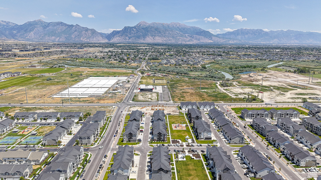 Aerial view of property and surrounding area featuring mountains and nearby suburban area